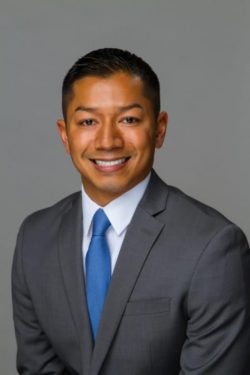 Man in a gray suit and blue tie smiling for a professional headshot