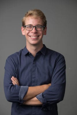 Man in glasses and a navy shirt with arms crossed for a professional headshot