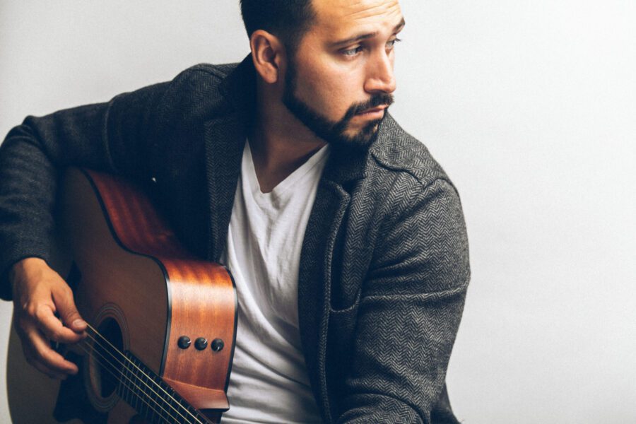 Musician in a gray jacket playing an acoustic guitar for a brand photography session