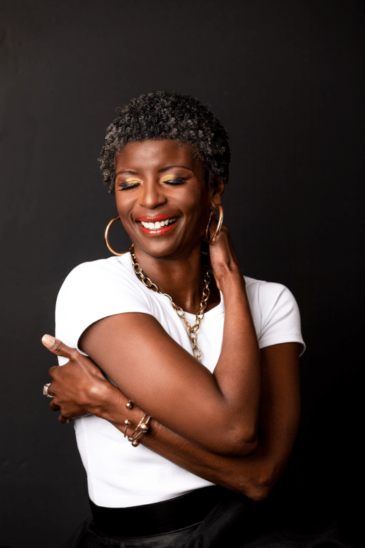 Older black woman smiling and hugging herself