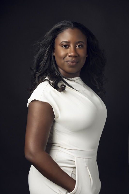 Woman in white outfit posing for a professional studio portrait against a dark background, Austin photography