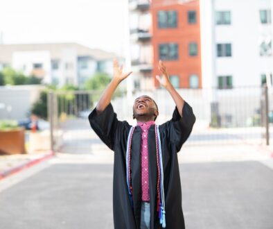 Graduate throwing their cap into the air in celebration on an Austin street