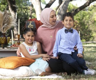 Mother and two children sitting together on a blanket at an outdoor picnic