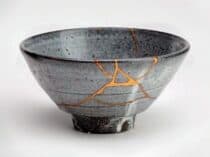 Gray ceramic bowl repaired in the Japanese kintsugi style with visible gold seams