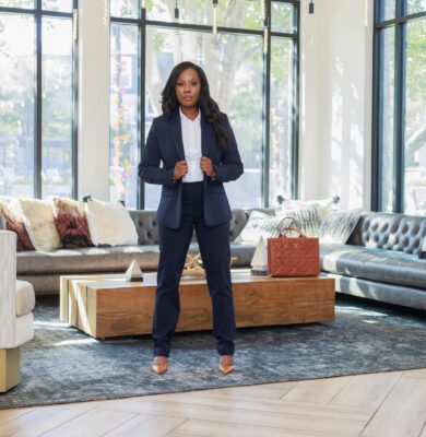 Attorney in a navy suit standing for a full-length portrait in a stylish office lounge