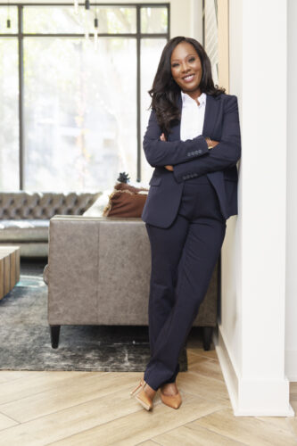 Attorney in a navy suit standing with arms crossed in an office lobby