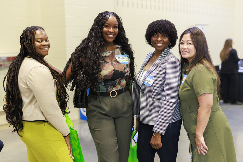 Four women smiling together at an Austin corporate networking event wearing name badges