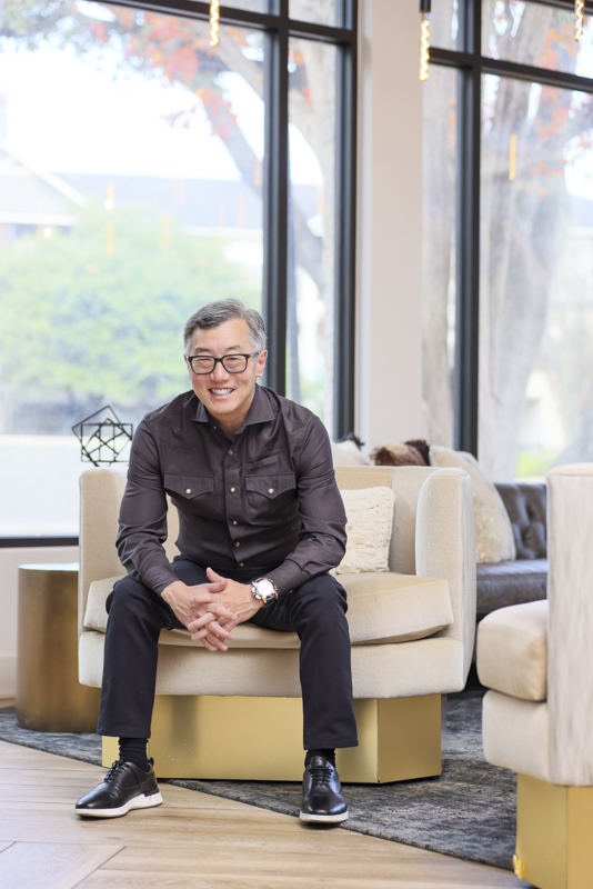 Smiling executive in a dark shirt seated on a couch in a modern office lounge for the Hyper Equity brand photography case study
