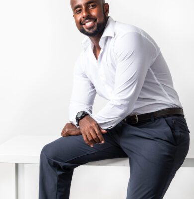 Smiling Black CEO in a white shirt sitting on a table in a studio branding portrait