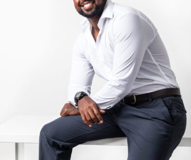 Smiling Black CEO in a white shirt sitting on a table in a studio branding portrait